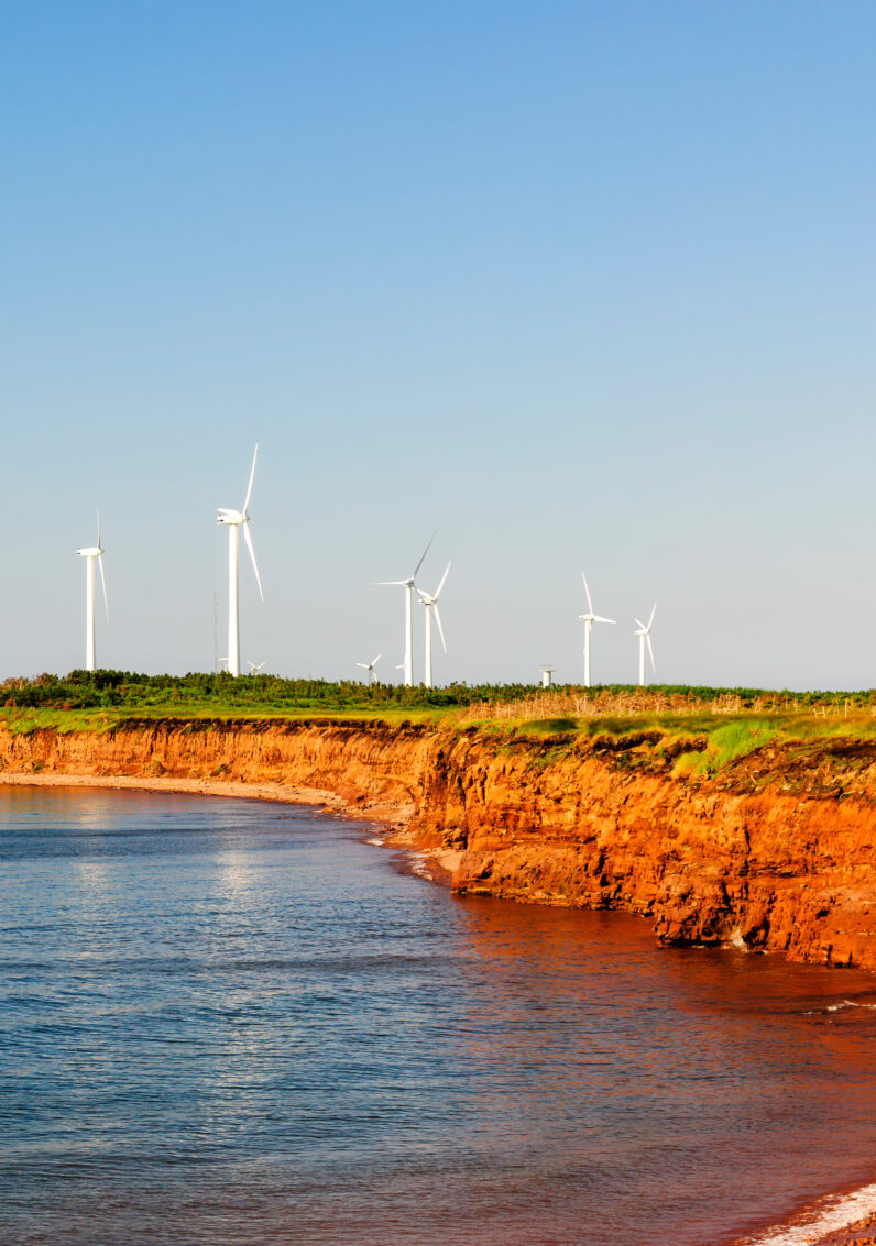 La côte de sable rouge de l’Île-du-Prince-Édouard avec des éoliennes en arrière-plan.