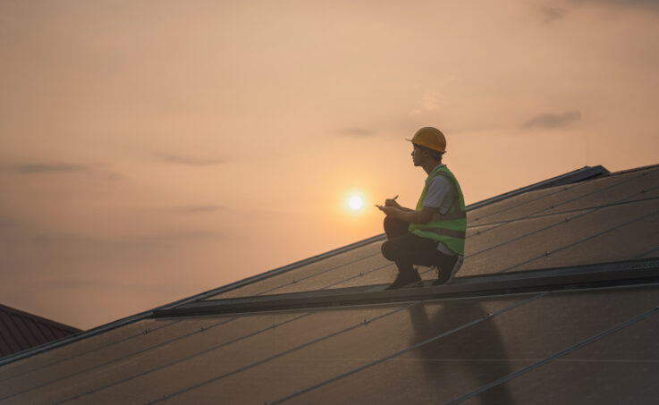 Electrical Worker Sitting on Solar Panels