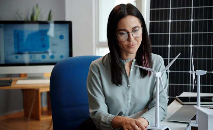 Professional woman looking at small model of wind turbine on her desk